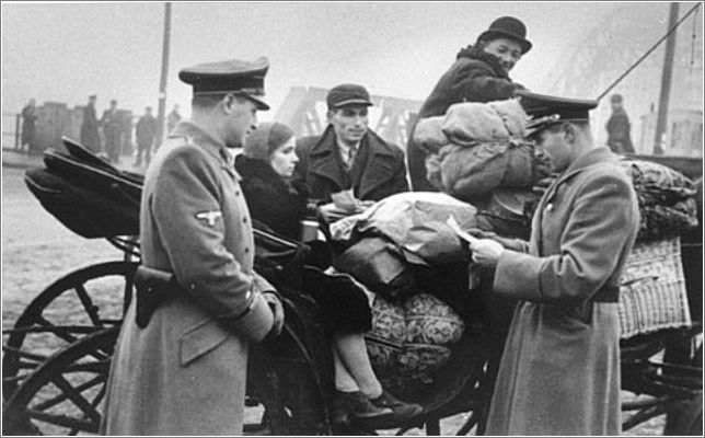 A German officer checks the papers of Jews moving into the Krakow ghetto